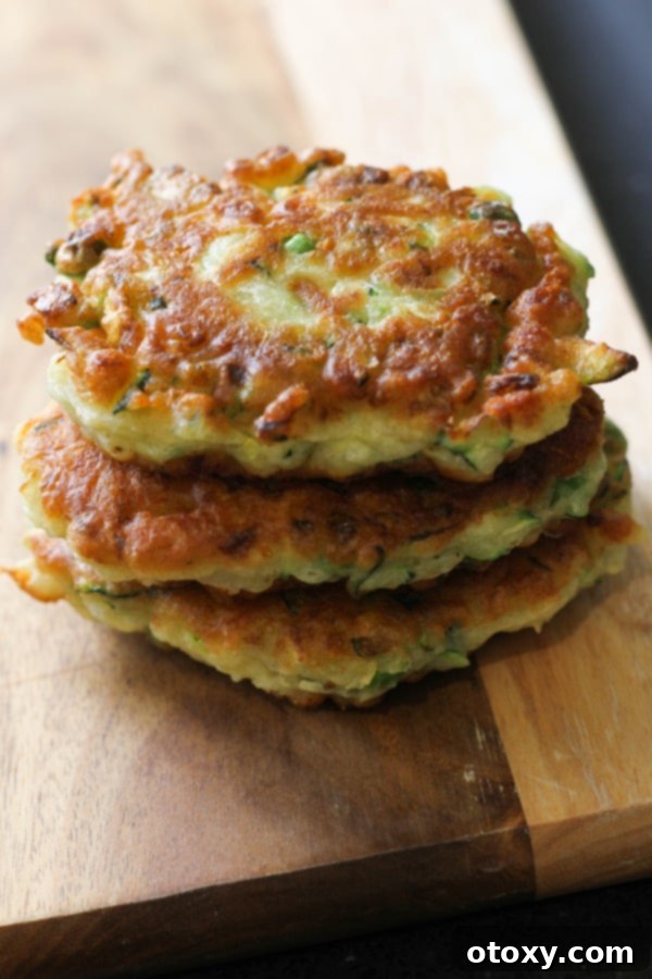Delicious pea & feta fritters stacked high on a rustic wooden board, ready to be served.