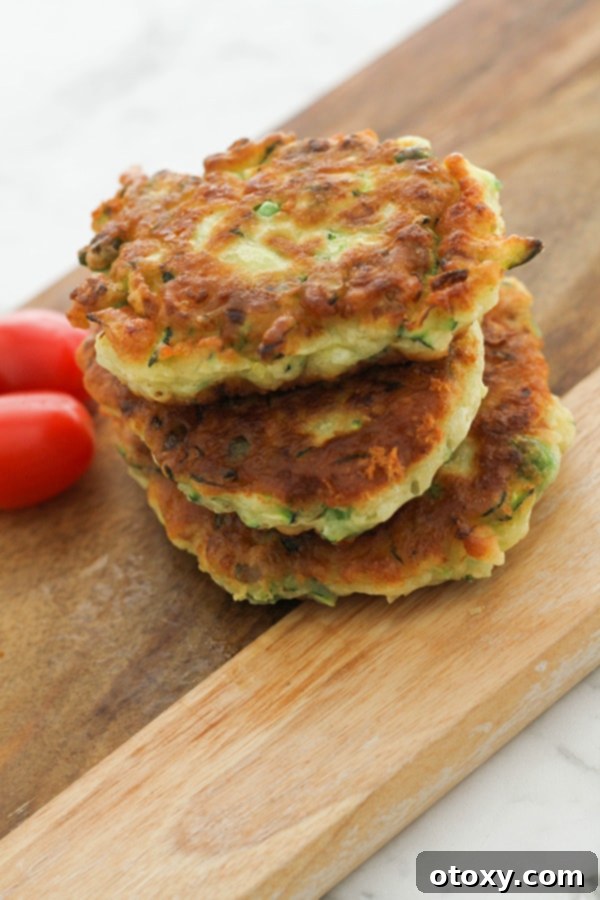 A stack of golden-brown pea & feta fritters artfully arranged on a rustic wooden serving board, ready to be enjoyed.