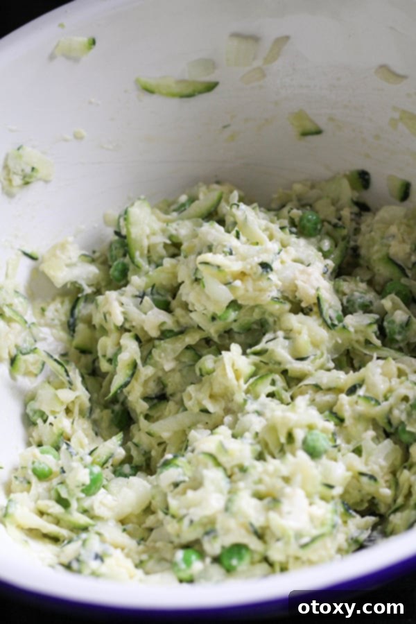 The fully mixed fritter batter in a white mixing bowl, showing a thick, cohesive texture with all ingredients evenly distributed.
