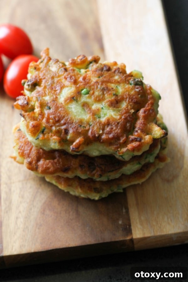 Reheated pea & feta fritters stacked appealingly on a wooden board, showcasing their golden texture and ready-to-eat appeal.