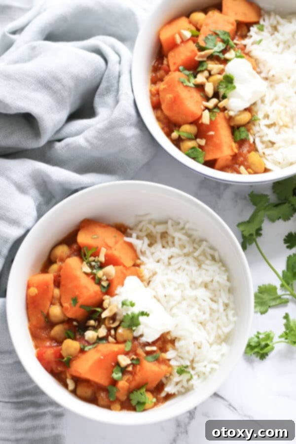 Golden Sweet Potato Lentil Bliss 2 Two bowls of vibrant sweet potato and lentil curry, garnished with fresh coriander, next to a textured grey napkin, symbolizing a cozy and healthy meal.