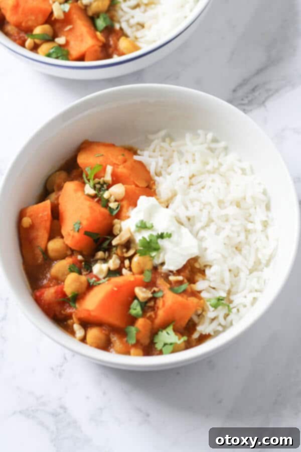 Golden Sweet Potato Lentil Bliss 7 A beautifully presented bowl of sweet potato, lentil, and chickpea curry, elegantly topped with fresh coriander, a dollop of yogurt, and crushed peanuts for added texture and flavor.