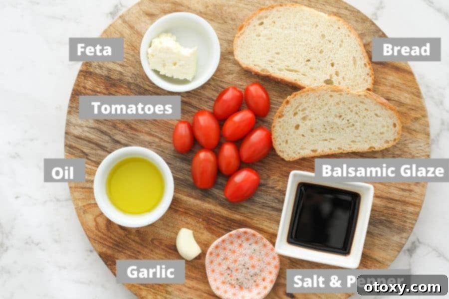 A selection of fresh ingredients including tomatoes, feta cheese, red onion, and olive oil, laid out on a wooden board.