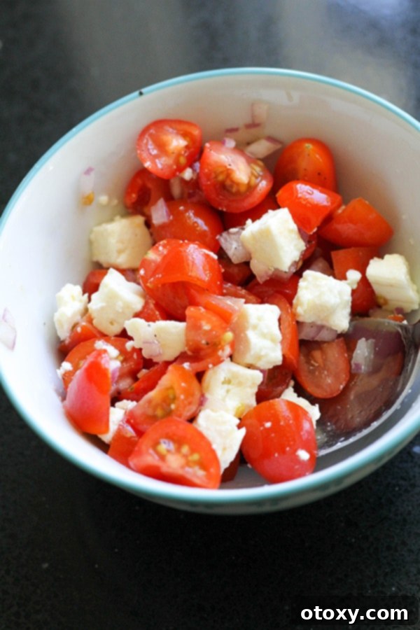 Finely diced tomatoes, chopped red onion, and crumbled feta cheese mixed together in a bowl.