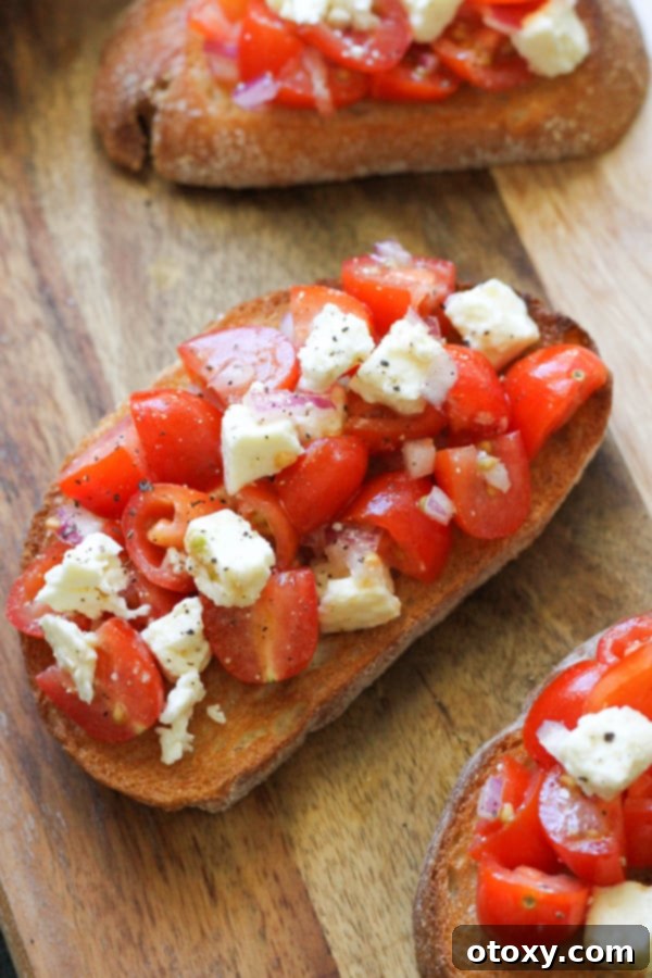A wooden serving board laden with multiple servings of tomato and feta bruschetta, ready for guests.