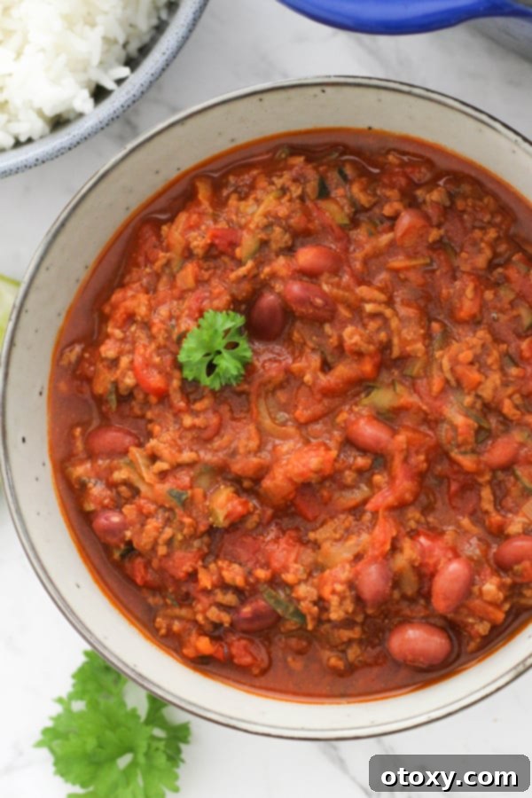 A large, inviting bowl of healthy Chilli Con Carne, garnished with fresh herbs, showcasing its rich texture and hearty ingredients.