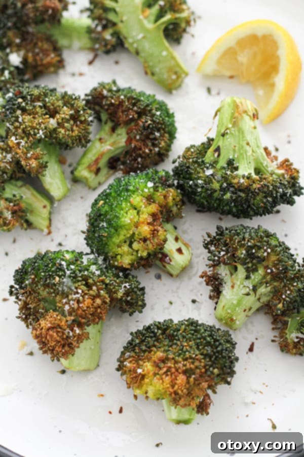 roasted broccoli on a white plate with lemon wedges.