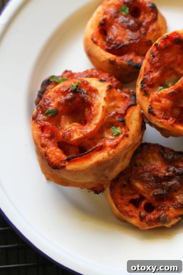 A fresh batch of Air Fryer Pizza Pinwheels beautifully arranged on a white serving plate, highlighting their golden crust and melted cheese.