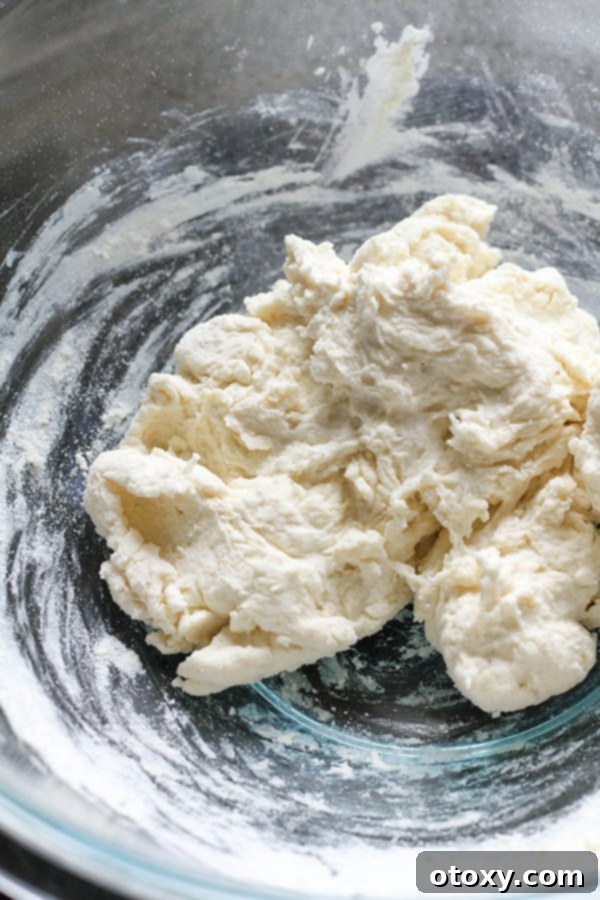 The two-ingredient dough, a smooth ball formed in a glass mixing bowl, ready for kneading.