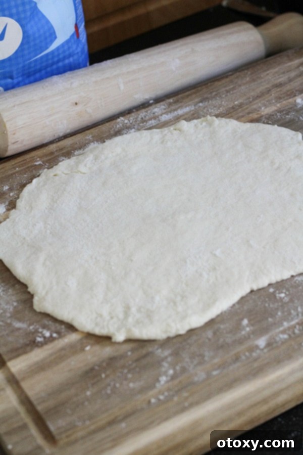 The two-ingredient dough rolled out into a rectangle on a wooden board, awaiting toppings.