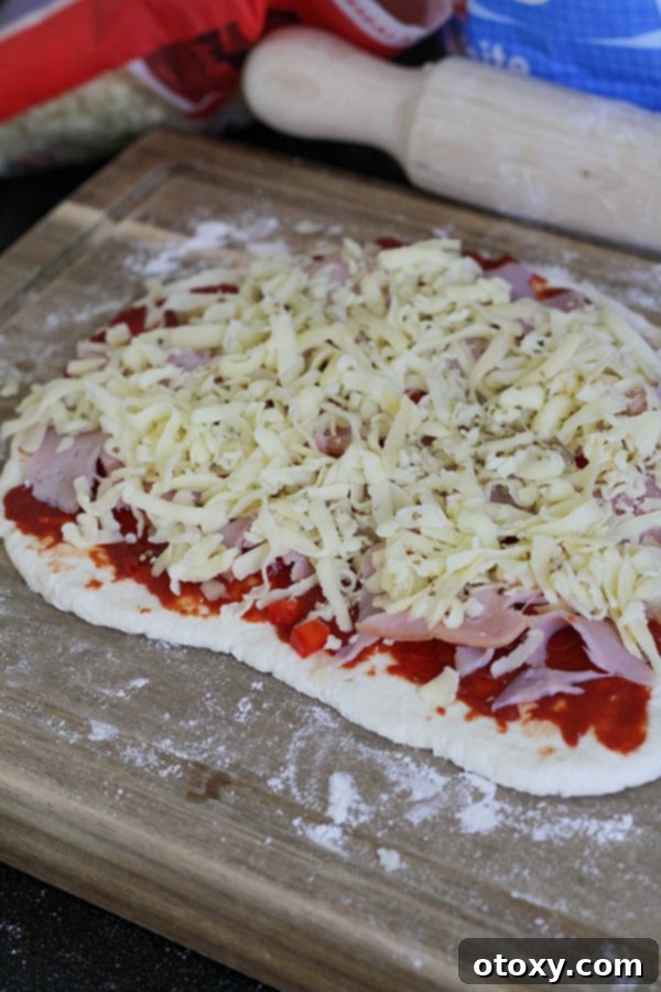 Dough beautifully layered with vibrant pizza toppings, ready to be rolled into pinwheels.