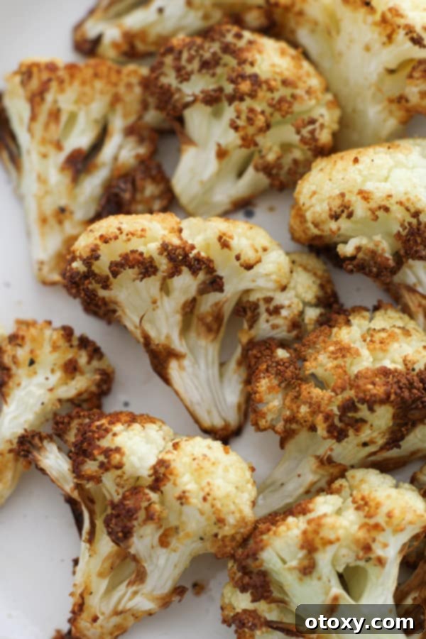 A serving of golden roasted cauliflower on a white plate, ready to be enjoyed.