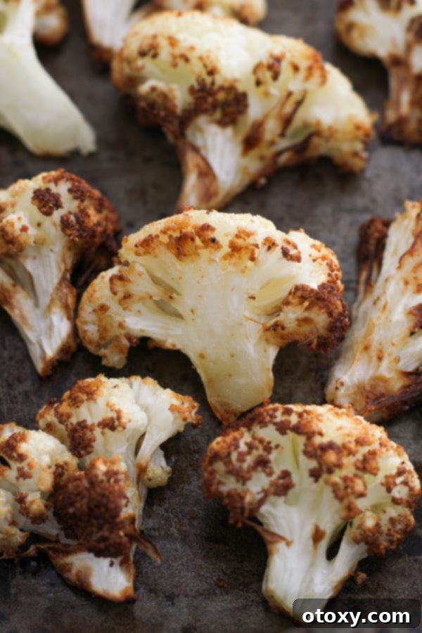 Close-up of roasted cauliflower florets neatly arranged on a baking tray, showing their golden-brown edges.