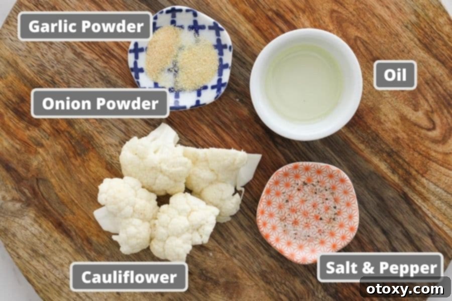 Fresh ingredients for roasted cauliflower, including a head of cauliflower, olive oil, and spices on a wooden board.