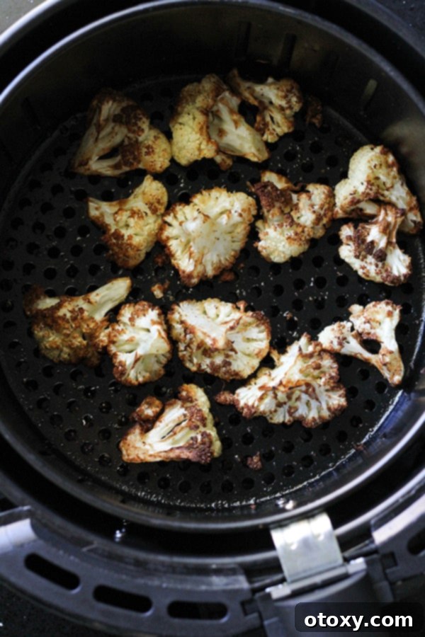 Crispy, golden-brown roasted cauliflower florets fresh out of the air fryer basket, perfectly cooked.