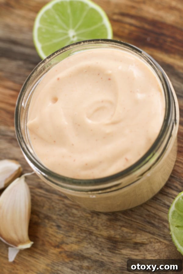 sriracha aioli in a glass jar on a wooden serving platter.