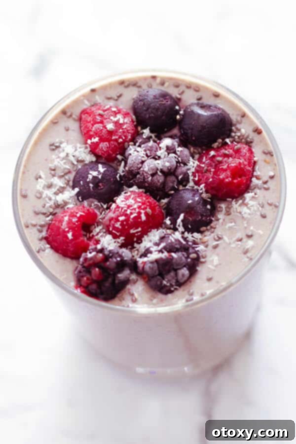 Tropical Burst Smoothie 2 berry green smoothie in a small glass topped with berries and desiccated coconut