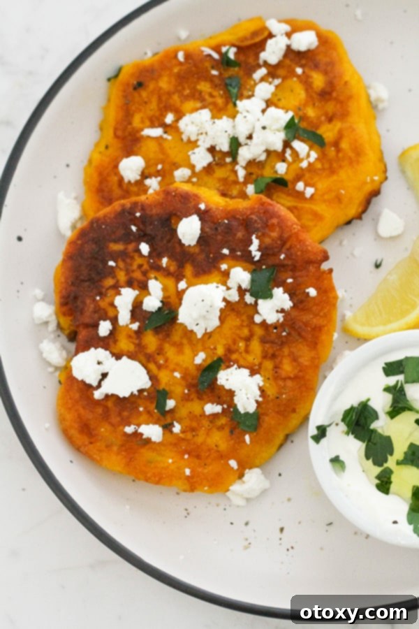 Golden Pumpkin Bites 2 two pumpkin fritters on a white plate topped with feta and parsley.