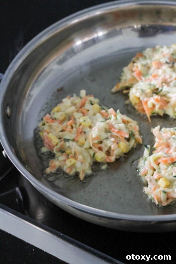 Golden Garden Fritters 8 Several vegetable fritters sizzling and cooking in a frying pan, turning golden brown.