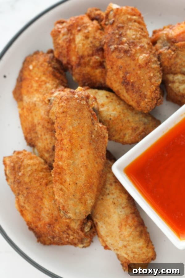Air-Fried Wing Perfection 2 A pristine white plate holds a generous serving of golden-brown, crispy air fryer chicken wings, ready to be devoured.