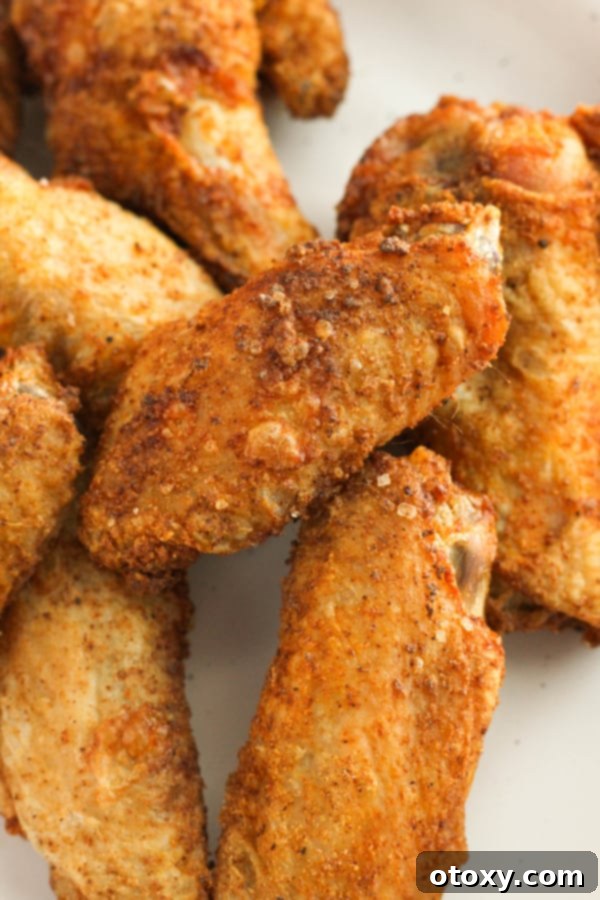Air-Fried Wing Perfection 11 A beautifully presented white plate showcases a mound of crispy, golden-brown air fryer chicken wings, ready to be enjoyed.