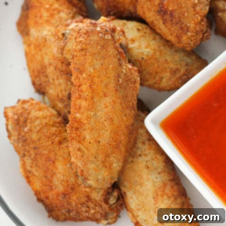 Air-Fried Wing Perfection 12 A pristine white plate holds a generous serving of golden-brown, crispy air fryer chicken wings.