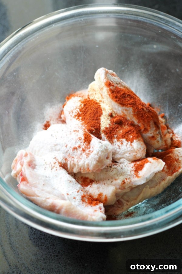 Air-Fried Wing Perfection 6 Raw chicken wings are shown in a mixing bowl, generously coated with baking powder and a blend of spices.