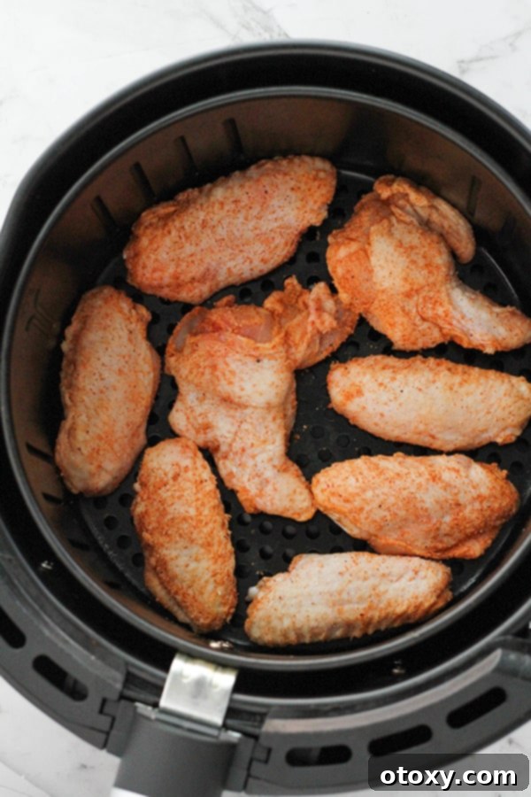 Air-Fried Wing Perfection 8 Seasoned chicken wings are neatly arranged in a single layer within an air fryer basket, ready for cooking.