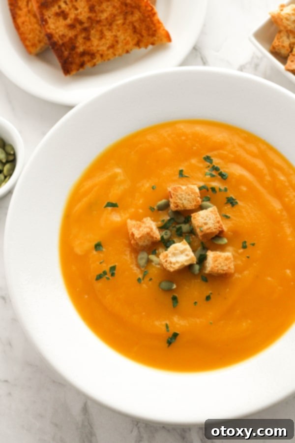 A beautifully presented bowl of creamy slow cooker pumpkin soup, garnished with crunchy croutons and a sprinkle of pumpkin seeds, ready to be enjoyed.