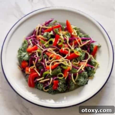 A vibrant crunchy kale salad with lemon tamari dressing, beautifully plated and ready to be served, showcasing its appealing colors and textures.