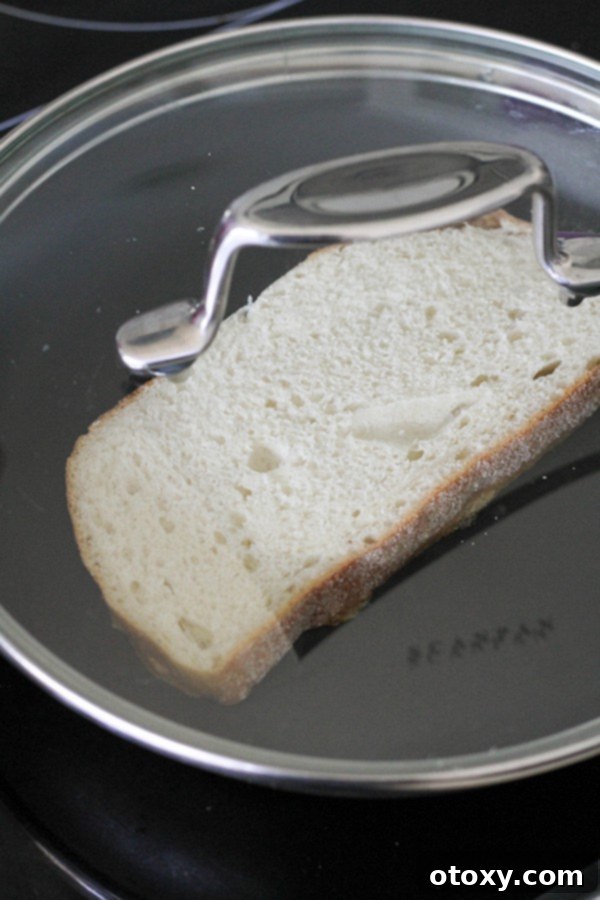slice of bread in a skillet with a lid on top.