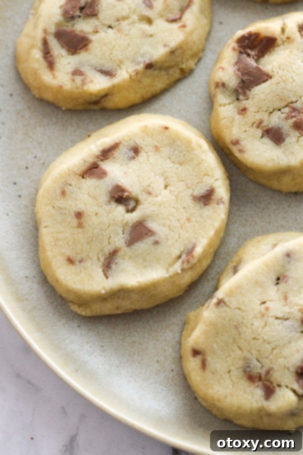 A stack of golden-brown shortbread cookies arranged neatly on a white plate, showcasing their perfect texture.