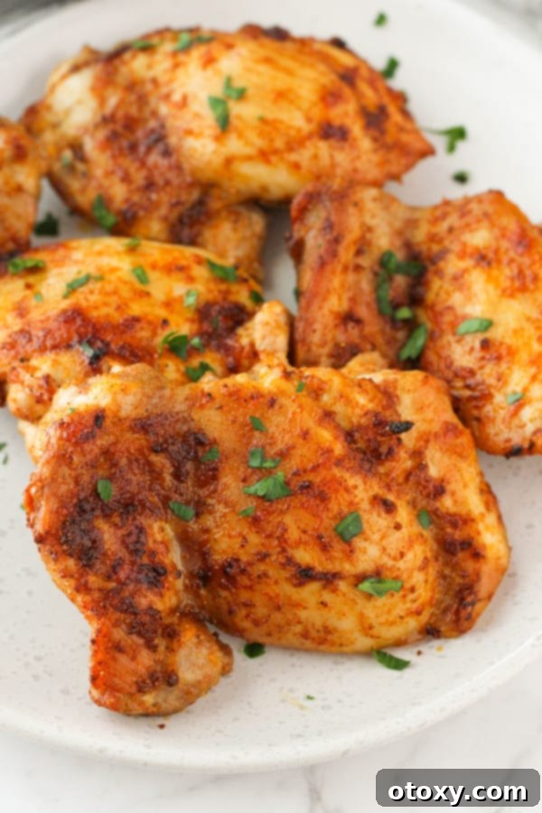 Ultimate Air Fryer Chicken Thighs 2 chicken thighs on a plate with parsley.