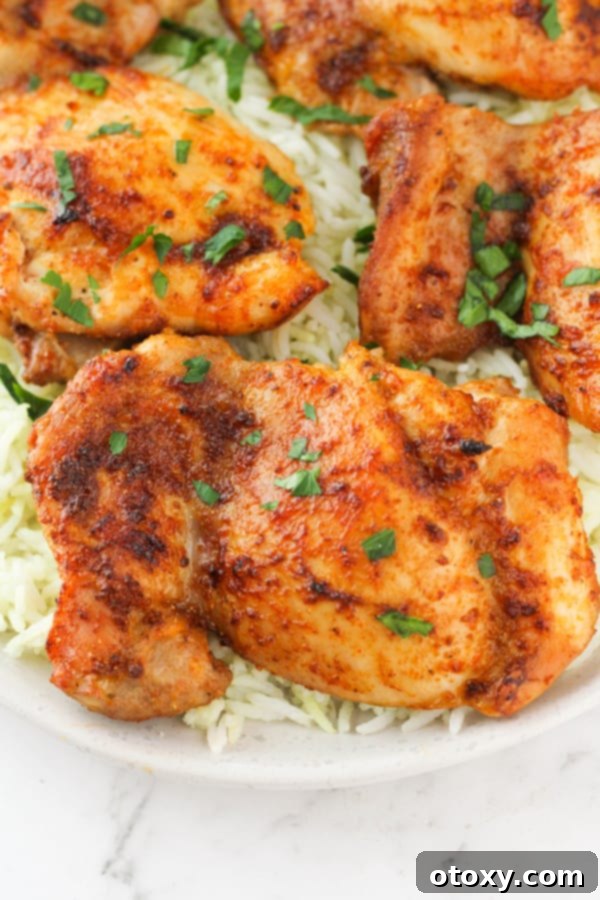 Ultimate Air Fryer Chicken Thighs 3 chicken thighs on top of a bed of rice with parsley.