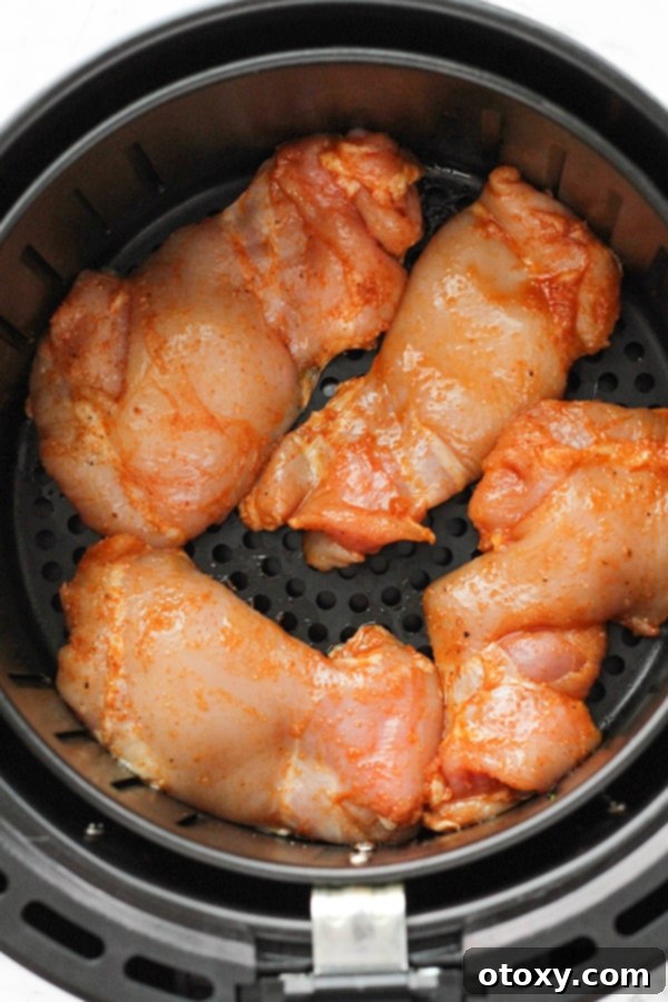 Ultimate Air Fryer Chicken Thighs 6 chicken thighs in an air fryer basket.