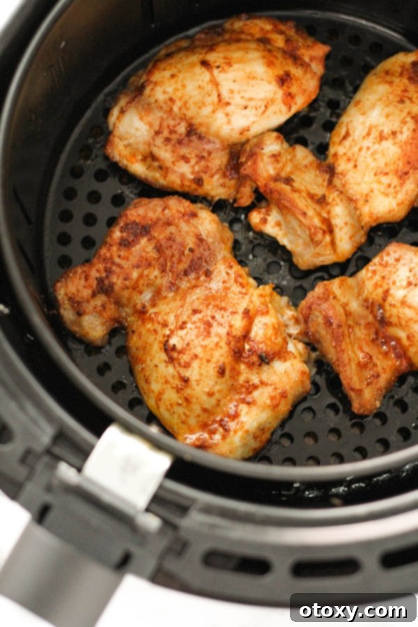 Ultimate Air Fryer Chicken Thighs 7 cooked chicken thighs in an air fryer basket.