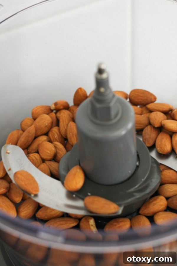 Tropical Date Energy Bites 4 Raw almonds being added to a food processor, ready for initial pulsing.