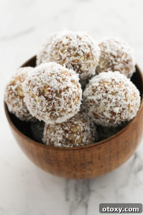 Tropical Date Energy Bites 9 A wooden bowl filled with an abundance of coconut date balls, inviting and ready to be enjoyed.