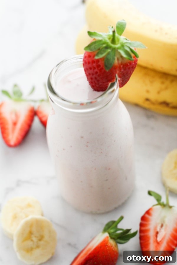 Smoothie in a small bottle topped with a fresh strawberry, ready to grab and go.