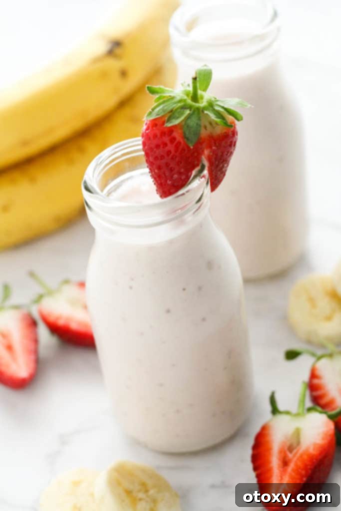 Smoothie in a small bottle topped with a strawberry, ready for enjoyment.
