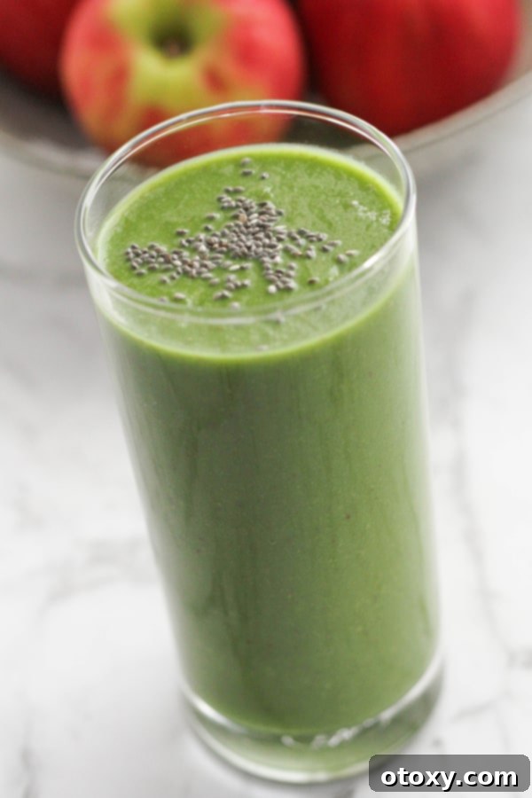 Vibrant Green Apple Smoothie 2 A vibrant green spinach apple smoothie in a tall glass, garnished with a sprinkle of chia seeds.