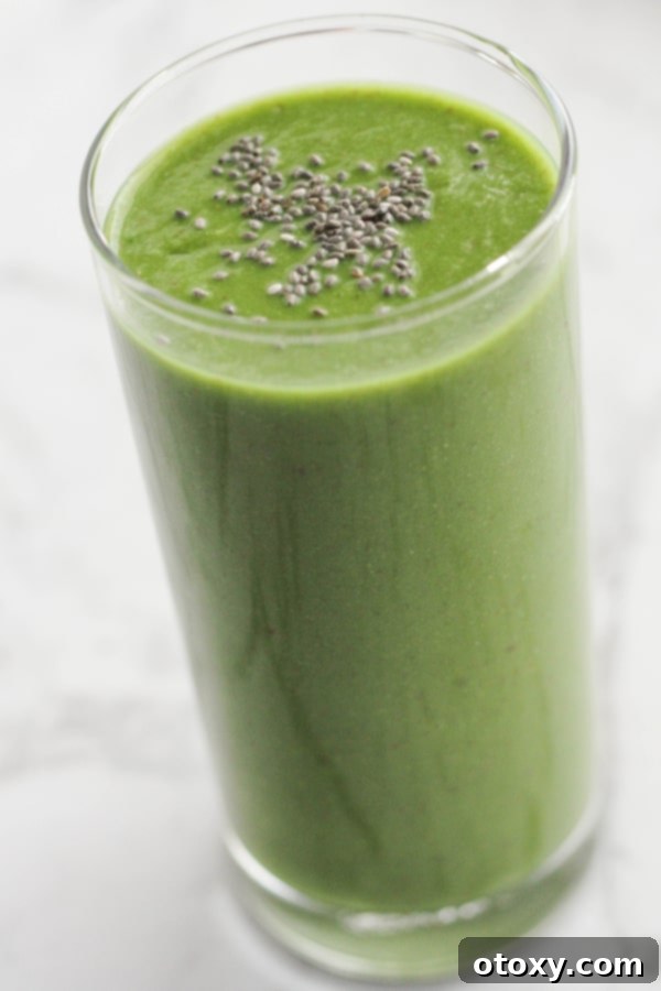 Vibrant Green Apple Smoothie 5 A tall glass filled with a bright green apple spinach smoothie, topped with a generous sprinkle of chia seeds for garnish.