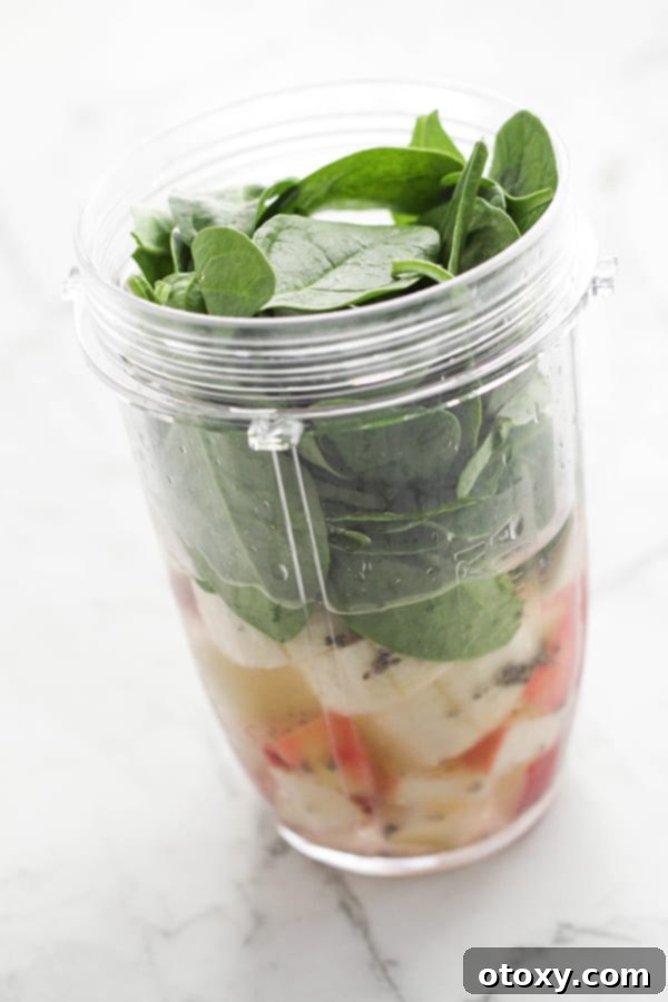 Vibrant Green Apple Smoothie 6 A blender cup filled with all the prepped ingredients for a spinach apple smoothie, ready for blending.