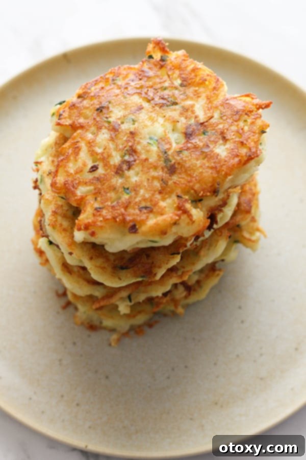 Another enticing stack of freshly cooked potato and zucchini fritters, highlighting their crisp exterior and inviting texture, perfect for a family meal.