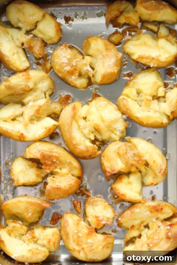 Annabel Crabb's Glass Potatoes, deeply golden and crispy, baking in a roasting pan inside the oven.