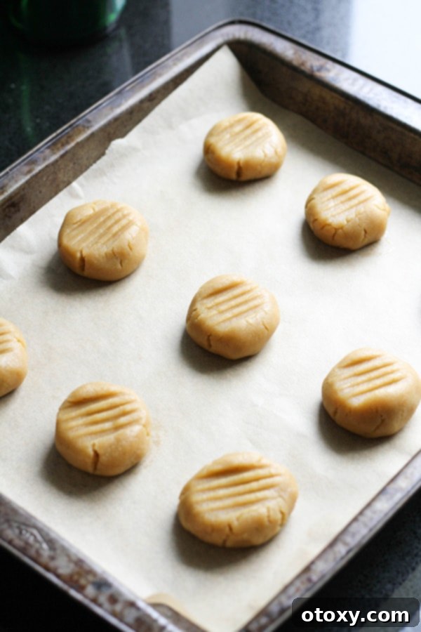 Unbaked golden syrup cookie dough balls on a baking tray, pressed with a fork and ready for the oven.