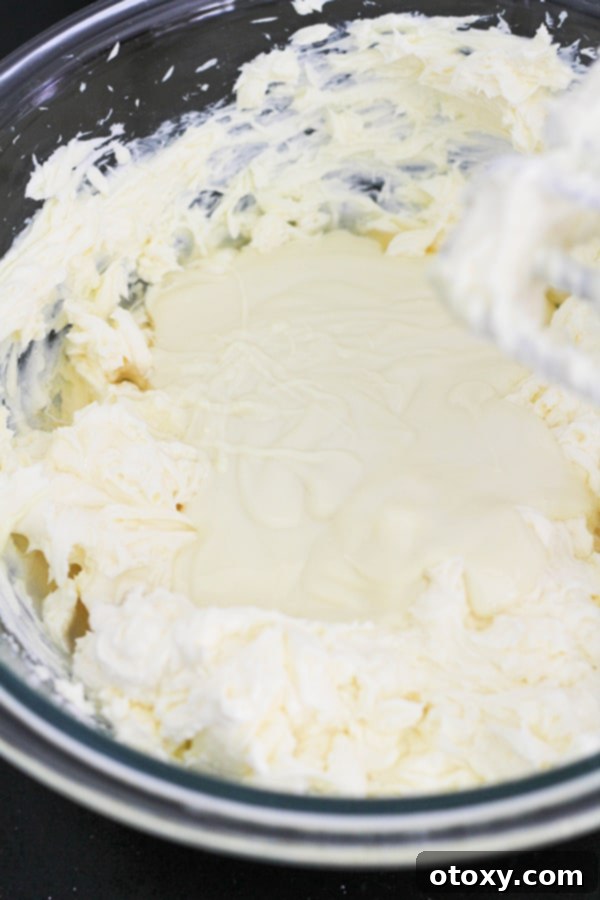 White chocolate and gelatin mixed into the cream cheese and sugar mixture in a large mixing bowl.
