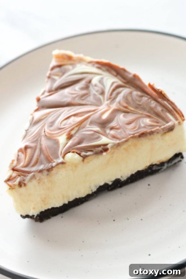 A pristine slice of no-bake marble cheesecake, highlighting the beautiful chocolate veins and creamy texture, served on a plain white plate.
