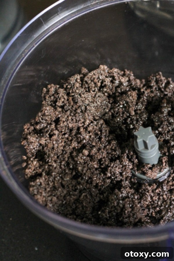 Oreo crumbs mixed with melted butter in a mixing bowl, ready for the crust.