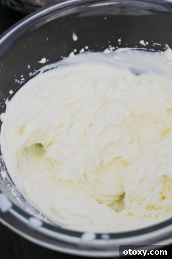 Freshly whipped cream with stiff peaks in a glass mixing bowl.